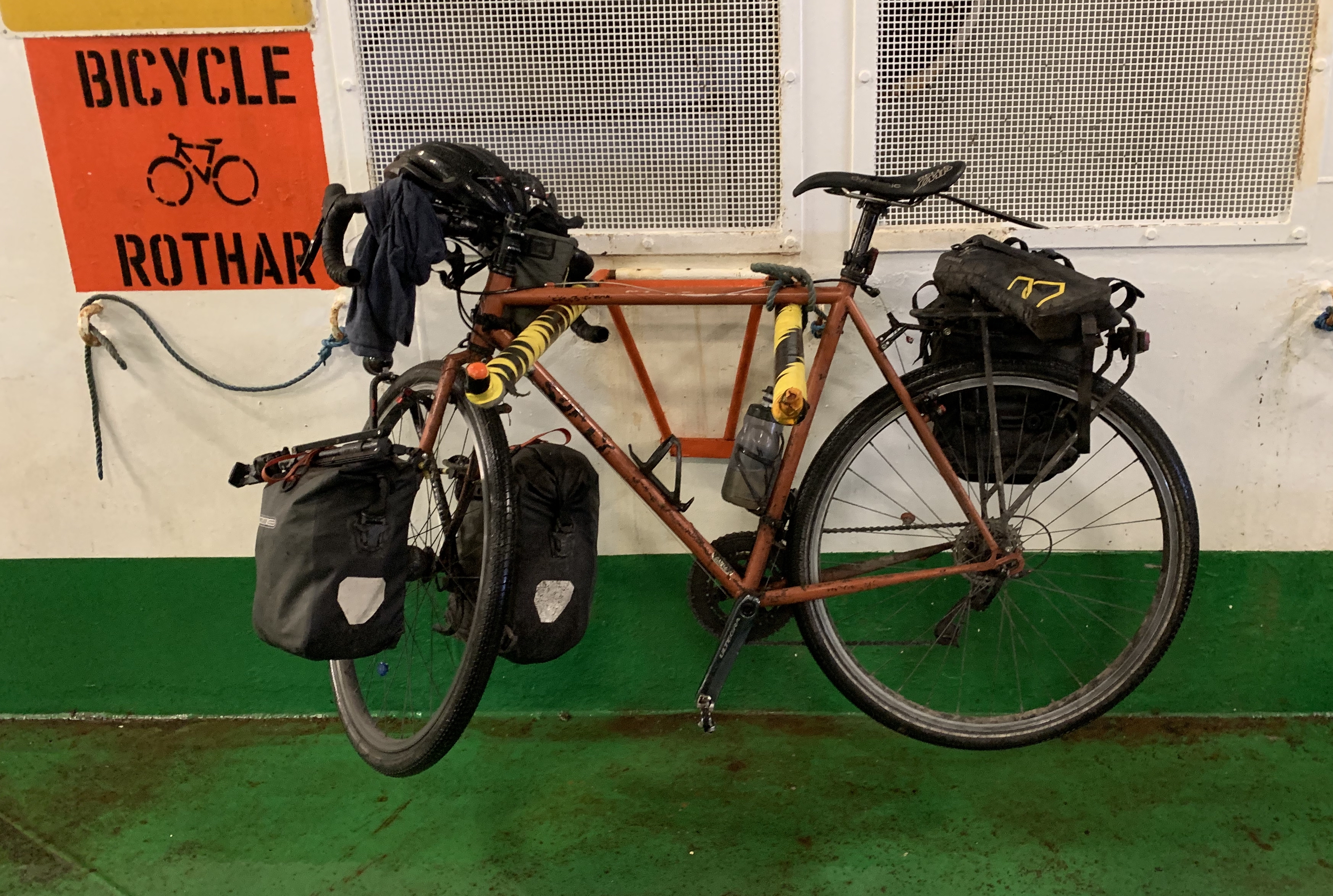 Touring bike on a nice two-pronged rack supporting the top bar and with an easy knot on one end